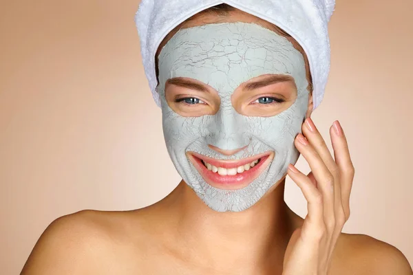 Laughing girl with clay facial mask