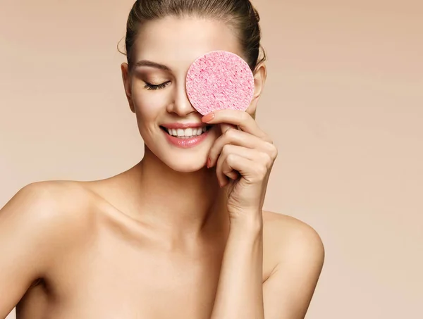 Funny girl holding pink sponge near her face.