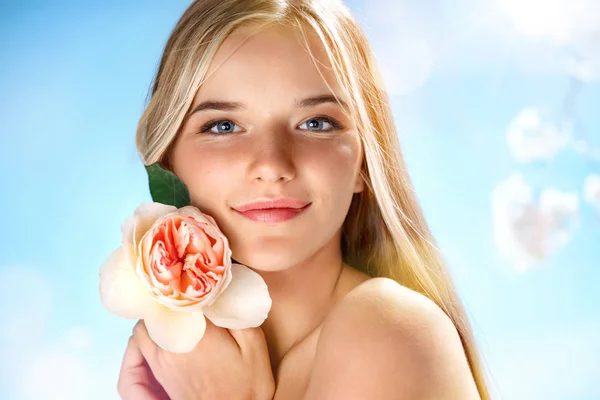 Cute young girl with rose. Youth and skin care concept. Spring