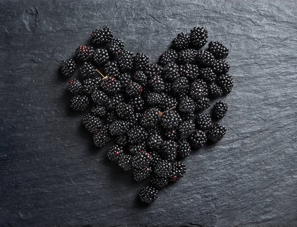 Heart made of blackberry on black slate. Top view. High resolution product.