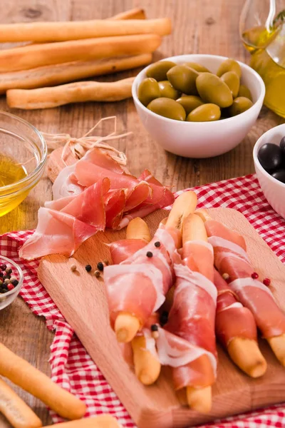 Grissini breadsticks with ham. — Stock Photo, Image