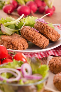 Beyaz tabak salataya köfteyle. 