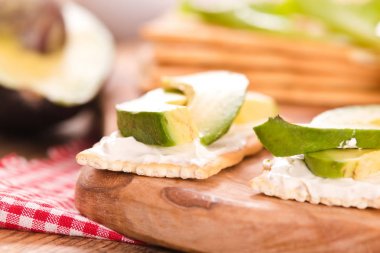 Jambon ve ahşap masa üzerinde avokado ile kraker.