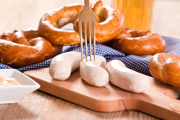 Bavarian pretzels with sausages on wooden table. — Stock Photo, Image