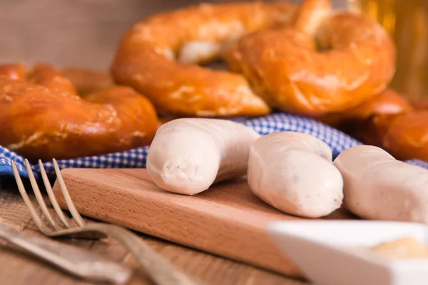 Bavarian pretzels with sausages on wooden table. — Stock Photo, Image