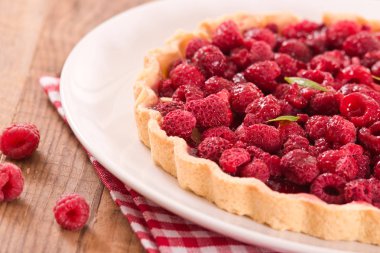 Beyaz çanak üzerinde ahududulu tart.