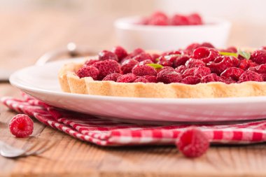 Beyaz çanak üzerinde ahududulu tart.