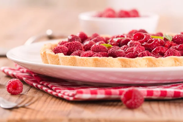 Beyaz çanak üzerinde ahududulu tart.