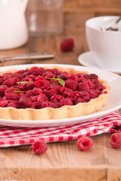 Beyaz çanak üzerinde ahududulu tart.