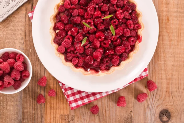 Beyaz çanak üzerinde ahududulu tart. 