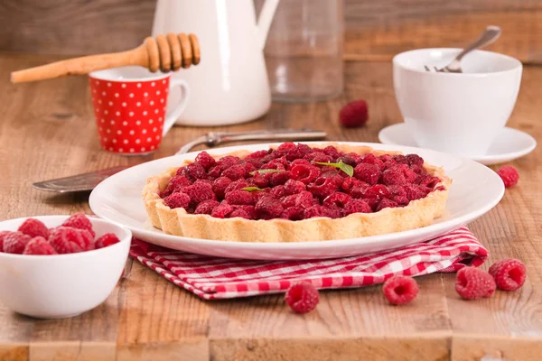 Beyaz çanak üzerinde ahududulu tart. 