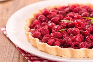 Beyaz çanak üzerinde ahududulu tart. 