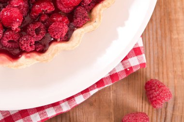 Beyaz çanak üzerinde ahududulu tart. 