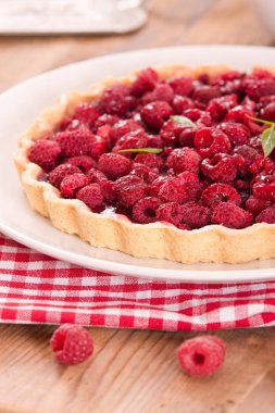 Beyaz çanak üzerinde ahududulu tart. 