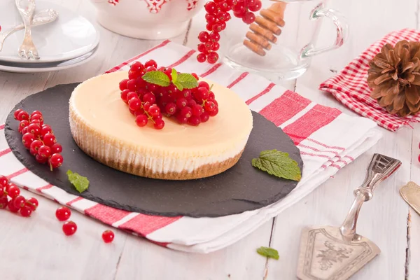 Redcurrant cheesecake on black dish.