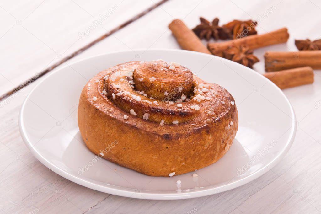 Cinnamon rolls with spices on white dish. 