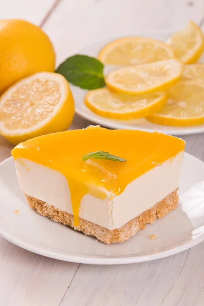 Lemon cheesecake on black dish.