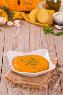 Beyaz tabakta balkabağı kremalı çorba.