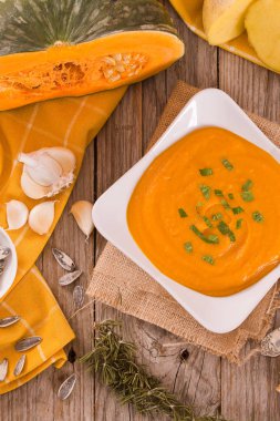 Beyaz tabakta balkabağı kremalı çorba.