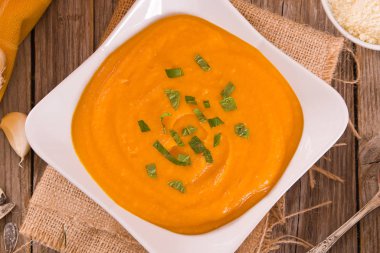 Beyaz tabakta balkabağı kremalı çorba.