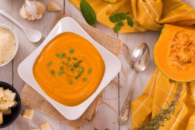 Beyaz tabakta balkabağı kremalı çorba.