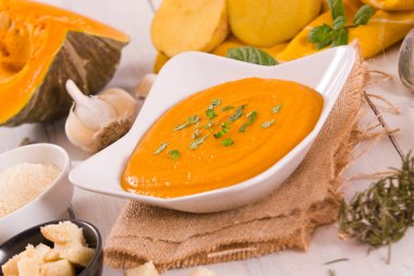 Beyaz tabakta balkabağı kremalı çorba.