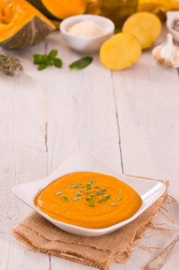 Beyaz tabakta balkabağı kremalı çorba.