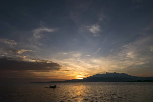 Tramonto con pescatore uomo pesca in una barca in mare vicino a Gili Air — Foto Stock