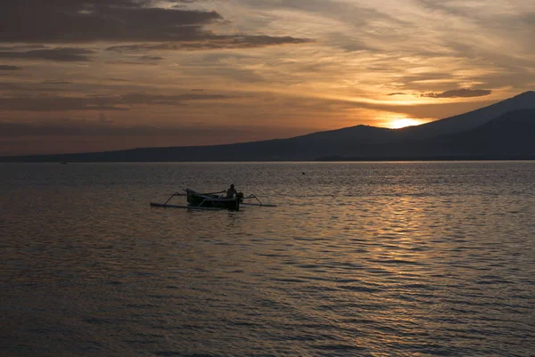 Tramonto con pescatore uomo pesca in una barca in mare vicino a Gili Air — Foto Stock
