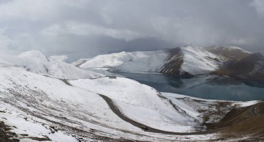 Tibet 'teki dostluk yolundaki Yamdrok Gölü' nün ayrıntıları dağlarda karla kaplı.