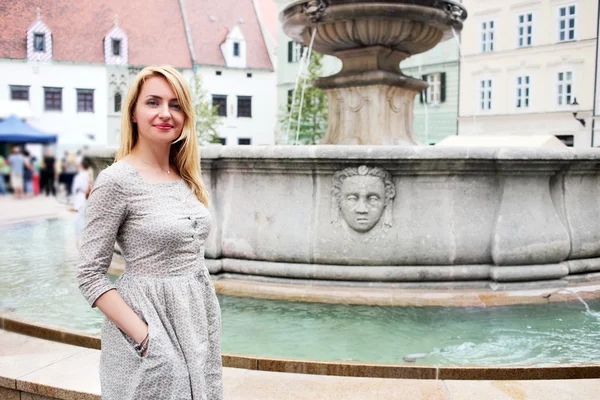 Frau posiert gegen Brunnen — Stockfoto