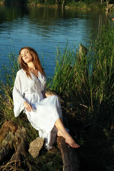 Mujer sentada a orillas del lago — Foto de Stock