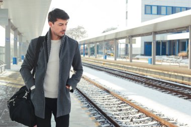 genç yakışıklı adam sıcak palto giyiyor tren istasyonunda ayakta açık portresi