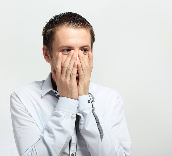 young man covering his face and looking over hands