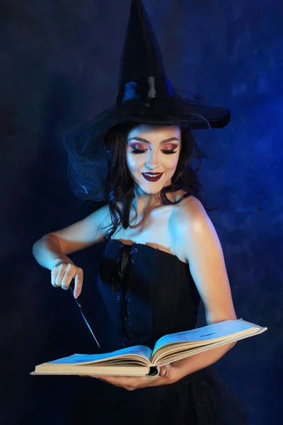 beautiful witch hold magic wand and reading spells from old book