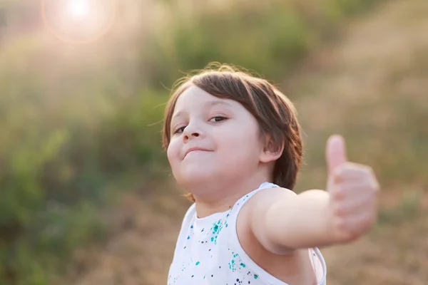 Улыбающийся Мальчик Показывает Большой Палец Вверх Зеленом Фоне Травы Копипространство — стоковое фото