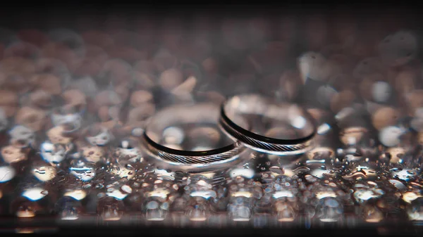 Silver wedding rings between drops