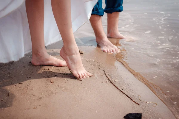 Les jambes des mariés dans une robe de mariée dans l'eau . — Photo