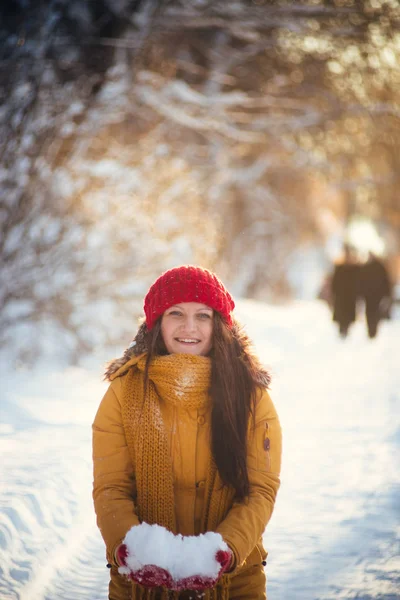 Charming girl in a yellow jacket and red cap throws snow in the air — Stock Photo, Image