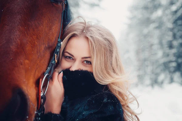 Portret van een mooi meisje in een zwarte jas, paard, winter — Stockfoto