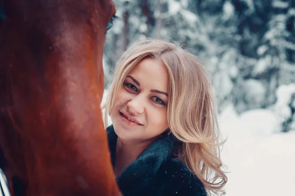 Portret van een mooi meisje in een zwarte jas, paard, winter — Stockfoto