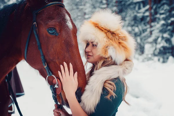 Portrait of a beautiful girl in green dress, cap from the fox, and horse in the winter on the nature — Stock Photo, Image