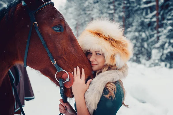 Portrait of a beautiful girl in green dress, cap from the fox, and horse in the winter on the nature — Stock Photo, Image