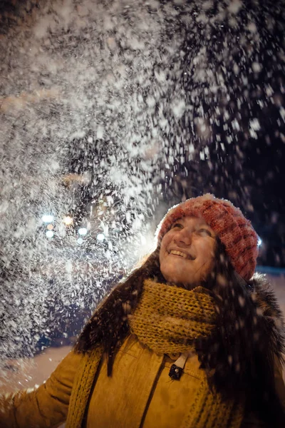 The girl's portrait in the winter who throws up snow. contrast in the light of city lamps. — Stock Photo, Image