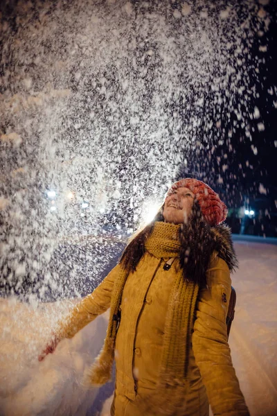 The girl's portrait in the winter who throws up snow. contrast in the light of city lamps. — Stock Photo, Image
