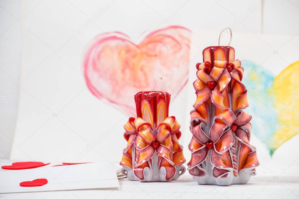 St. Valentine's Day: two carved candles of orange color against the background  pink heart.