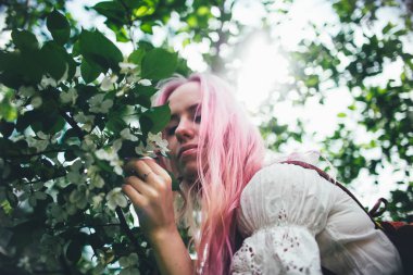 Pembe saçlı güzel kız çiçek açması elma ağacı arasında yaz aylarında gezer.