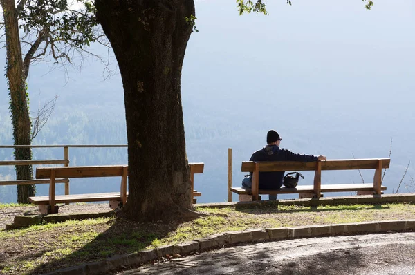 Homem solitário sentado no banco com bela vista das montanhas. Parque e a floresta — Fotografia de Stock