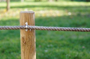 Kalın halatlar ile ahşap bir kazık yeşil çayır korur.