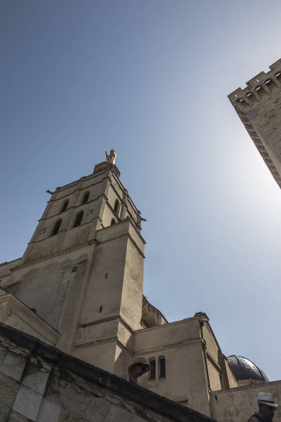 Avignon cathedral (Cathedral of Our Lady of Doms) next to Papal palace (Palais des Papes) under blue sky in Avignon, France